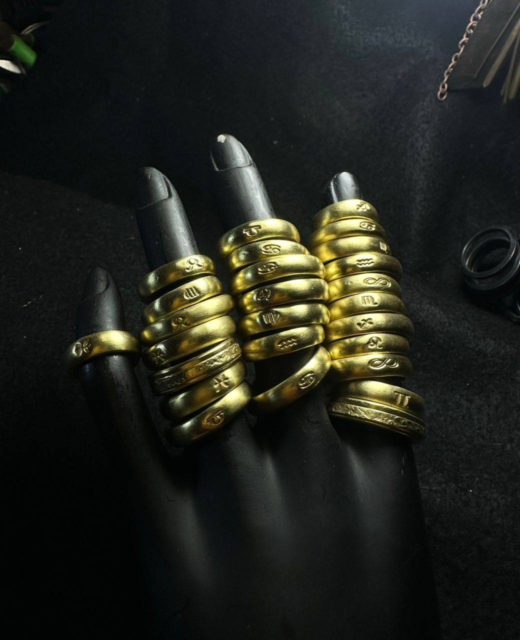 Rows of brass rings engraved with zodiac and symbol designs on black display fingers